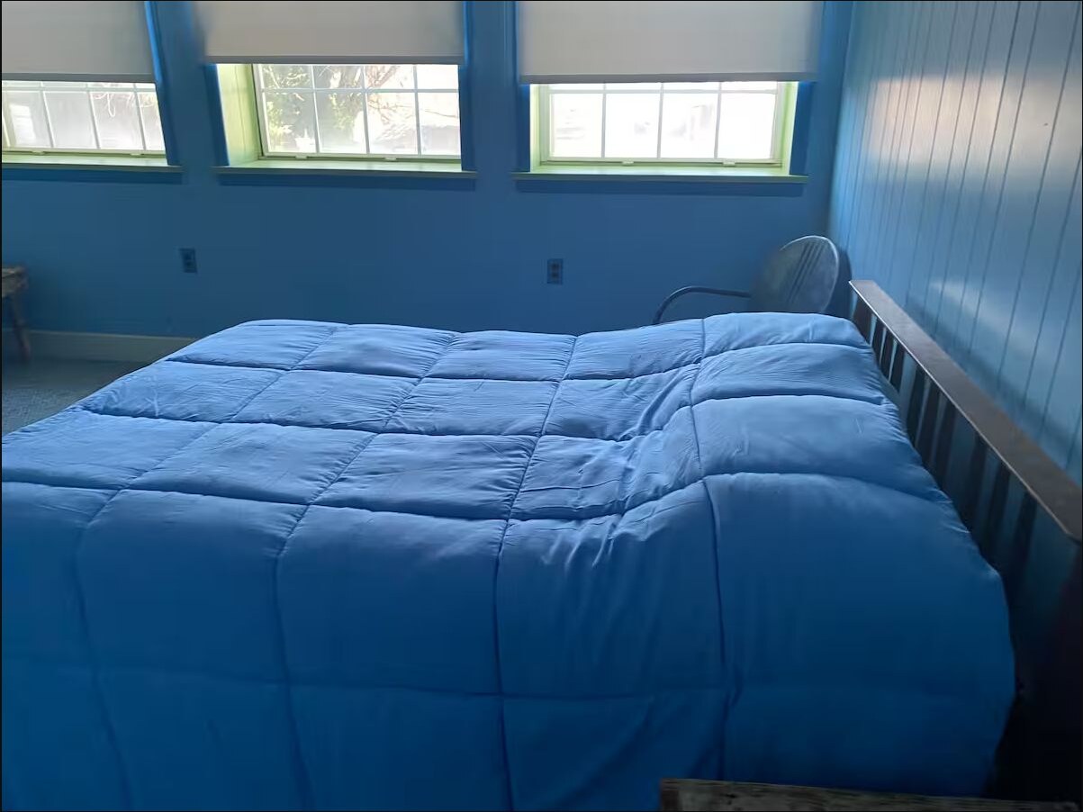 Blue bedroom with a large bed and three windows