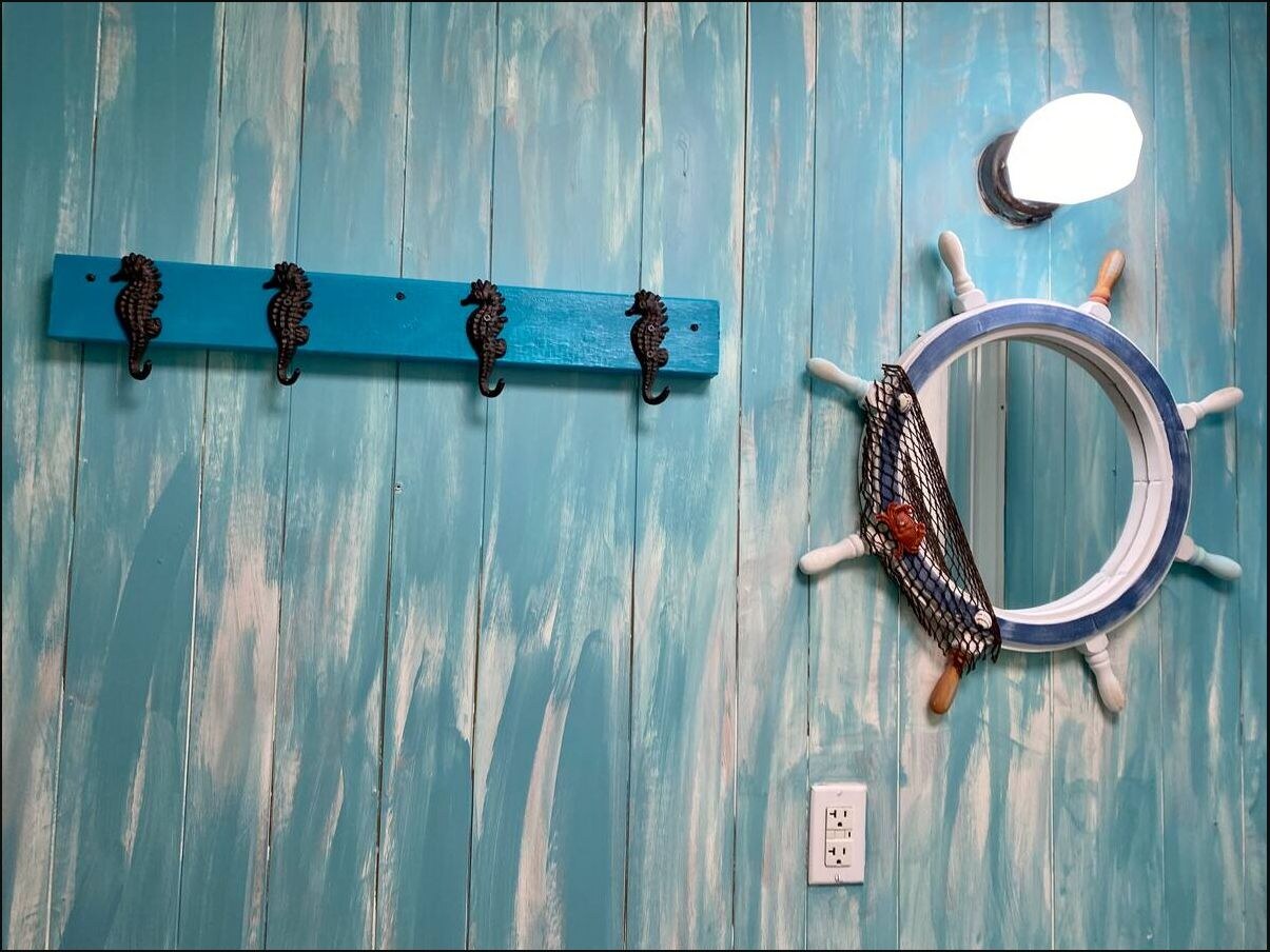Ship wheel mirror and seahorse hooks in the bathroom