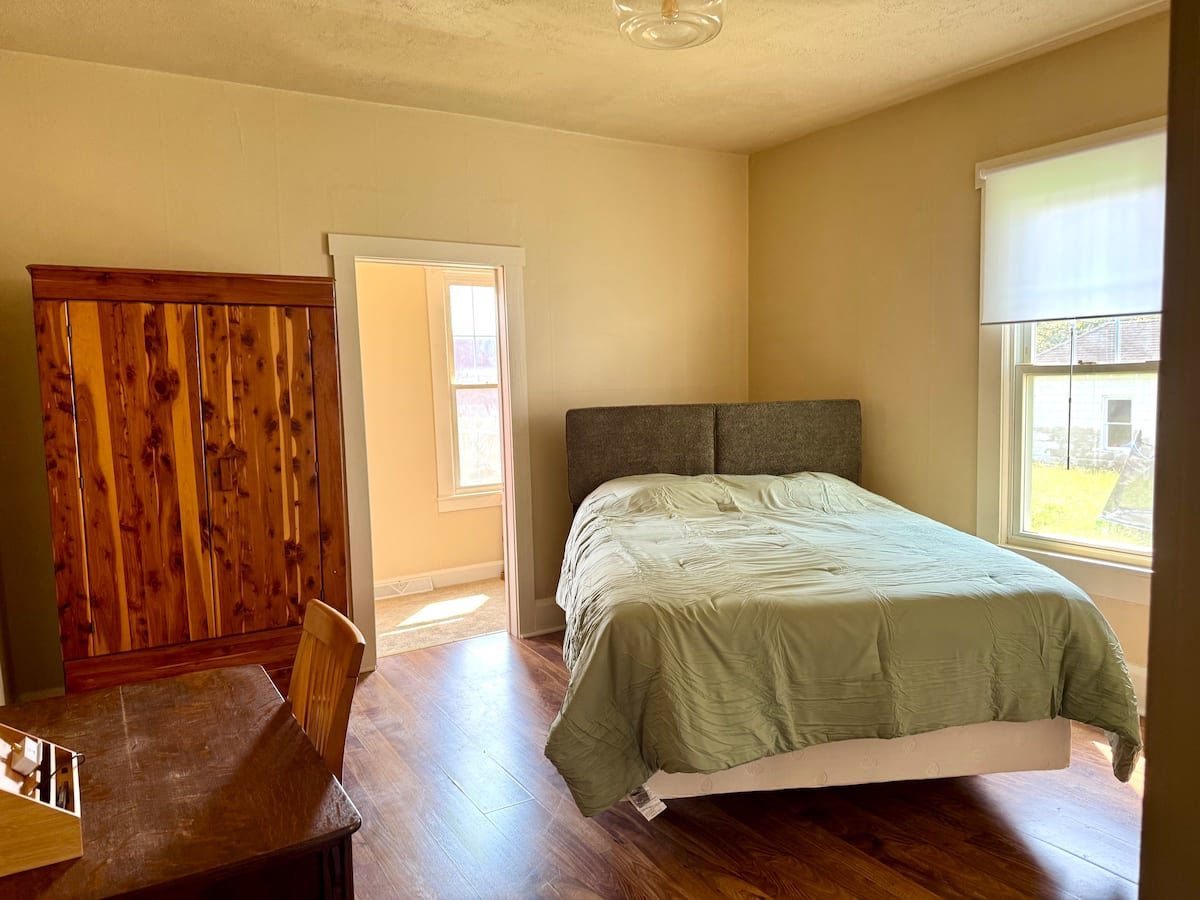 Queen bedroom with hardwood floors and antique wardrobe